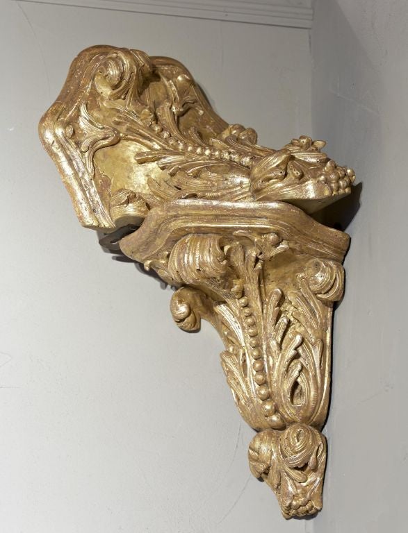 A very unusual pair of large George II giltwood corner brackets with acanthus leaf and floral carved bodies and retaining the original forged iron hangers. These brackets were designed for a specific purpose as in supporting a heavy element such as