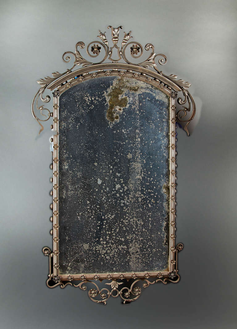 A large cast and forged steel and iron pier mirror with foliate crest and apron. The rectangular bevelled plate is surrounded by a molded frame with concentric applied rosettes. Late 19th century, probably American or English. Great form in an