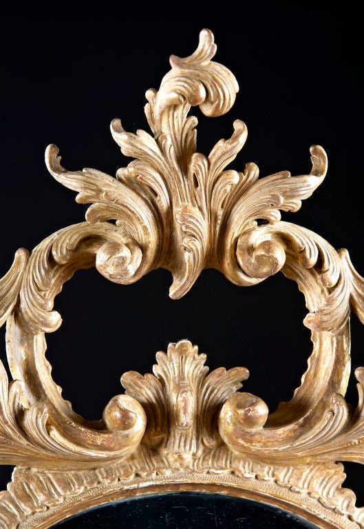 An oval giltwood Chippendale mirror with foliate and leaf carved framework, English, circa 1760. Appears to retain an older gilt surface. Plate replaced.