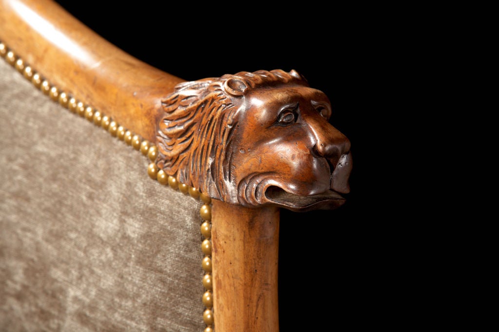 A dramatic pair of large scaled Italian walnut tub chairs with carved lion hand holds and realistic carved legs ending in paw feet. The crests are finished with walnut rails forming a very comfortable 