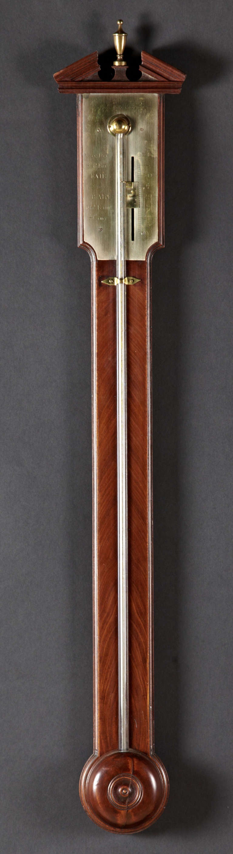 A mahogany stick barometer with pitched pediment and open face with disc turned cistern cover. Early 19th century.