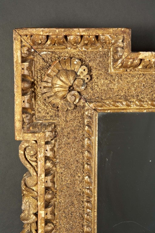 A George II giltwood frame. The blocked corners are fitted with applied, stylized shells on sand cast ground. The borders are carved with egg and dart motifs. The sides are carved with husk draperies. This piece which probably started out as a