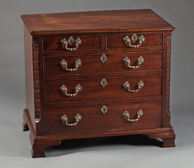 A diminutive American mahogany chest of drawers with fretwork corners on ogee bracket feet. The molded edge top over a configuration of two small drawers over three larger graduated drawers with cockbeaded edges and flanked by canted corners with