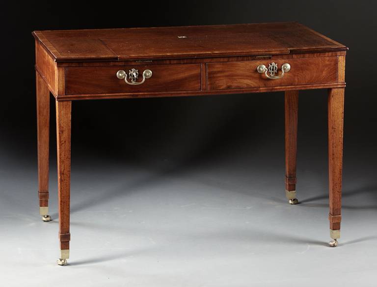 A mahogany two drawer writing table with a ratchet supported writing tablet. The rectangular case with a cross banded and molded edge top has a centered drawing tablet. The whole supported by four tapered square legs with raised cuffs ending in