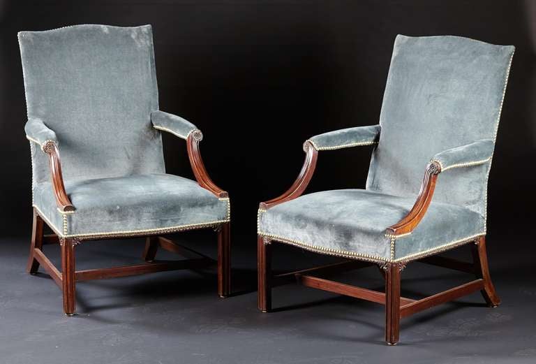 A fine pair of English Georgian marlborough leg gainsborough chairs in mahogany. The upholstered backs with cupids bow crests are supported by molded, incurved arms with rosettes over serpentine seats with carved egg and dart edges on molded