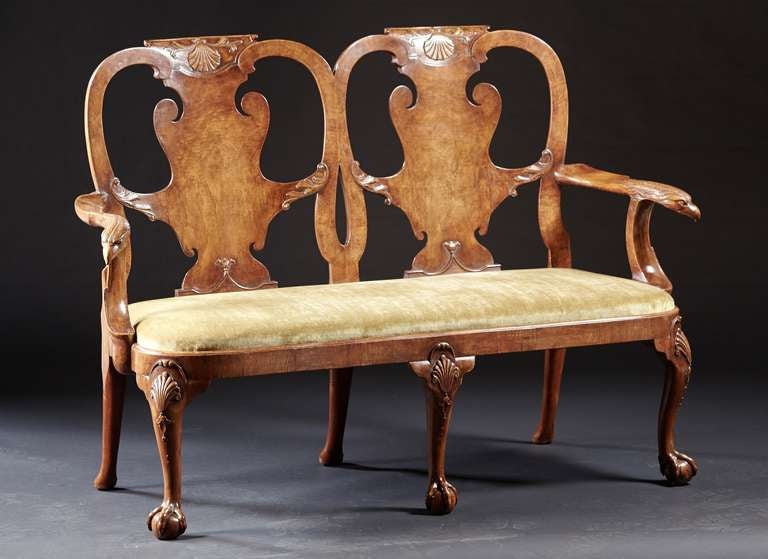 A classic walnut carved and veneered double chairback settee with eagle head arms supported by cabriole legs ending in ball and claw feet. Each chairback is veneered with figural walnut and carved appliques within shaped crests and stiles. The