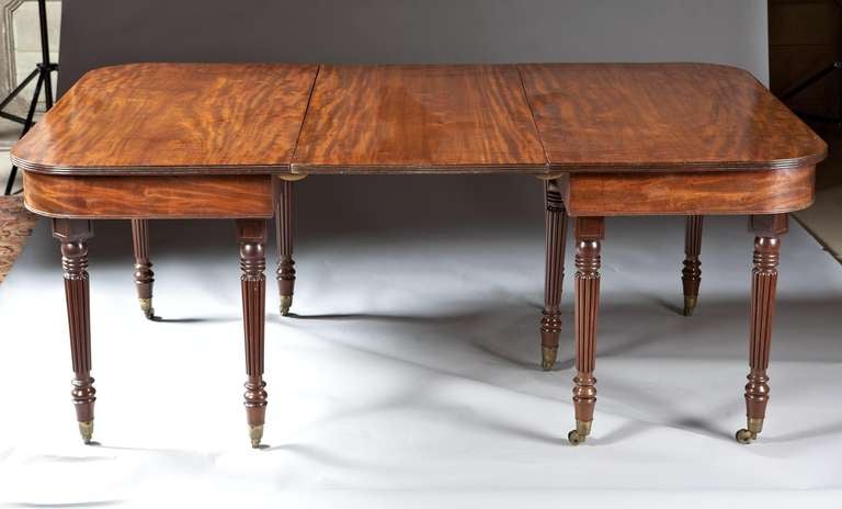 A Regency period mahogany extension dining table from the second quarter of the 19th century. Each rounded corner end with reeded edge top supported by ring turned and reeded tapered legs ending in brass cup casters. This table has the finest color