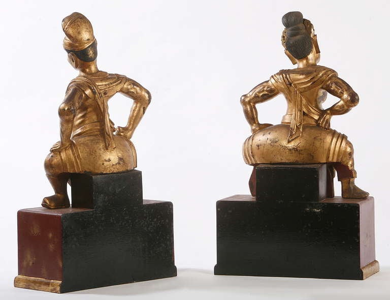 A pair of boldly carved and gilded temple guardians
on later faux lacquer stands.