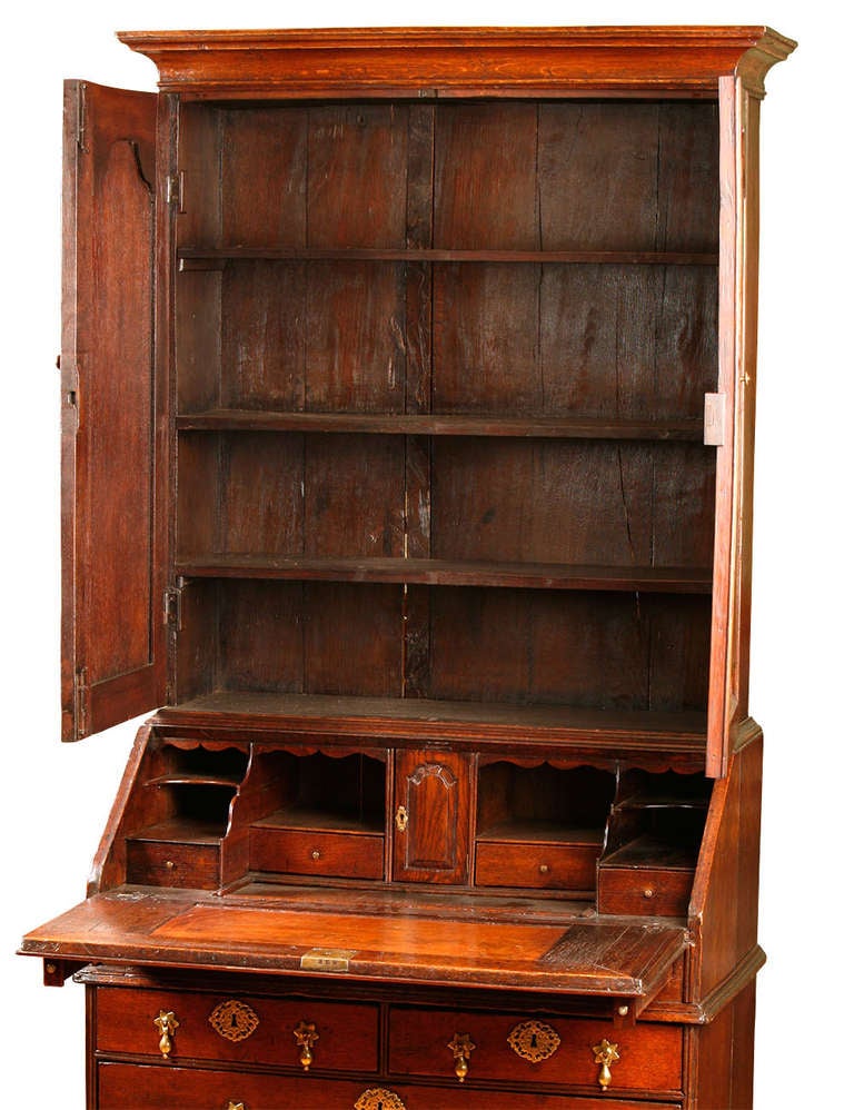 The upper section with raised shaped panel doors, the base with
a slant front having an interior with stepped drawers and a well,
beneath the interior are two small and two larger drawers all supported
on later ball feet.