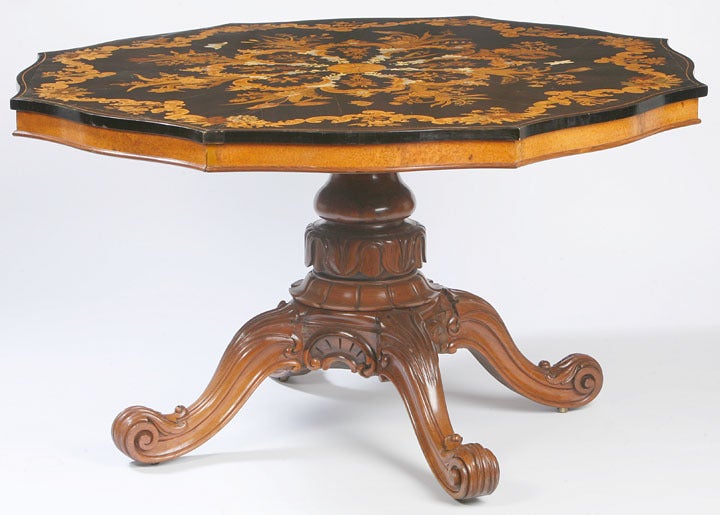 A profusely inlaid center table the top with with butterflies and floral marquetry
the base with boldly carved details