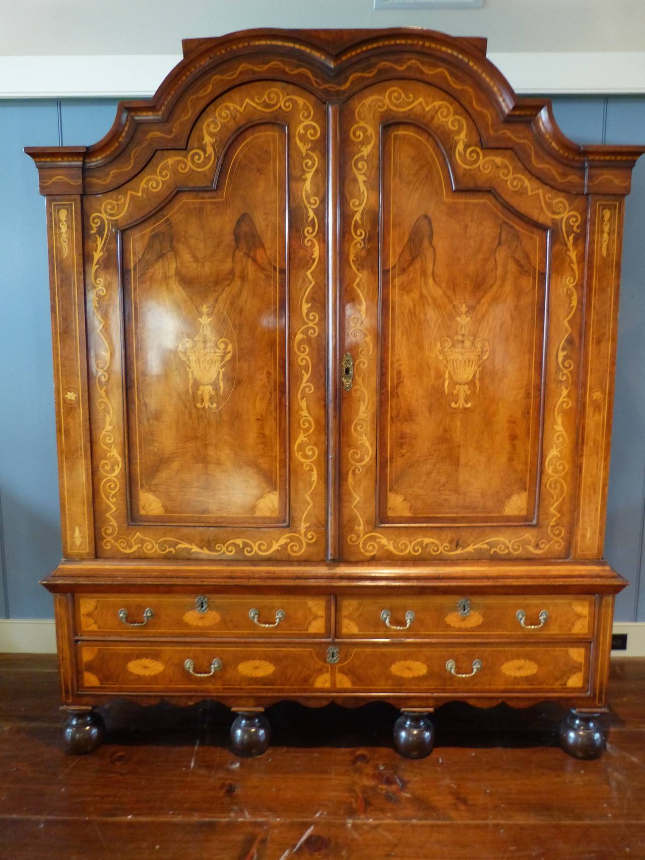 A fine Circassian walnut and oak Dutch, early 18th century kast. The double doors inlaid with neoclassical vases, surrounded by interloping vines, on a base with two short and one long drawer all resting on wavy apron and four bun feet. The interior