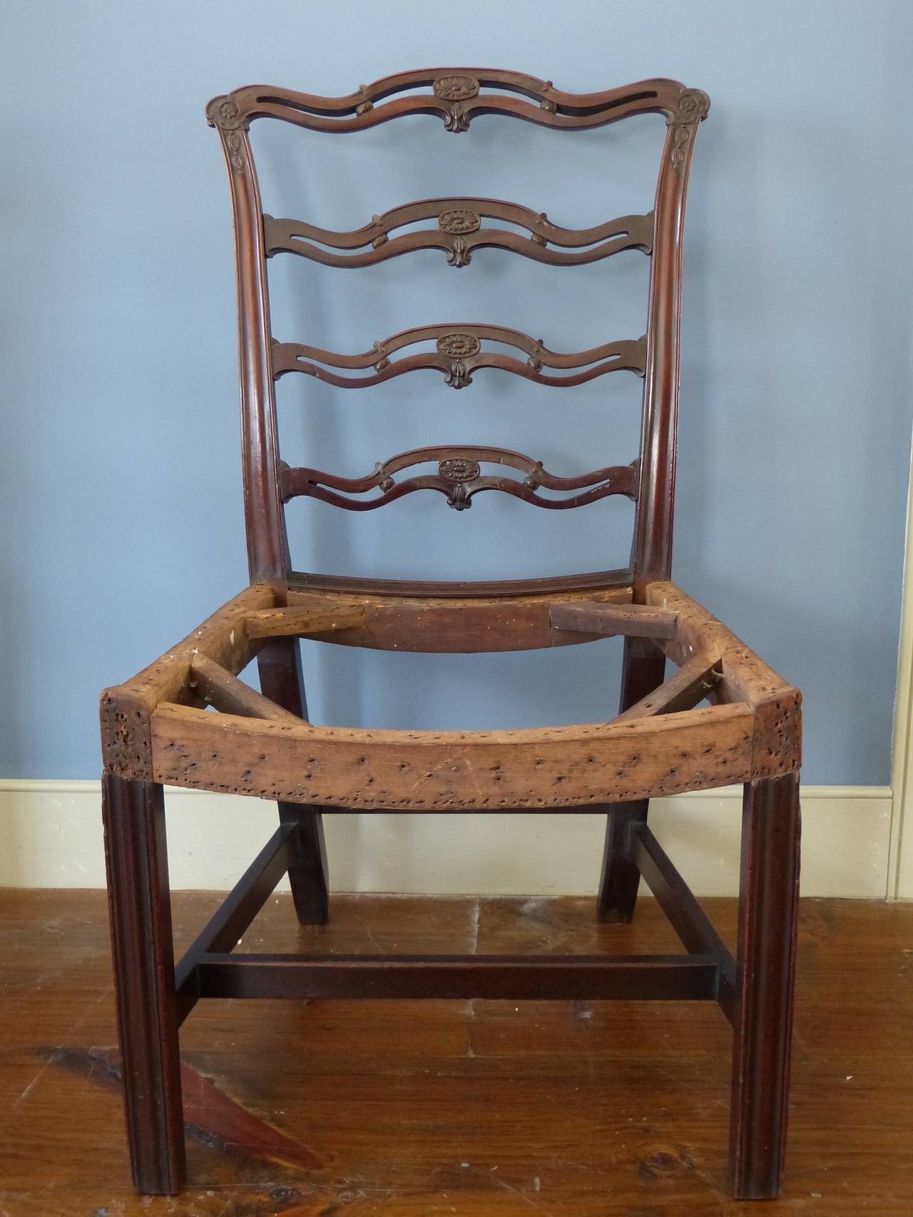 A very fine quality pair of 18th century Georgian mahogany ladder backside chairs with saddle seats and square fluted tapering legs. The shaped ladder backs with carved central rosettes and inverted bellflower carvings to top rail, English, circa