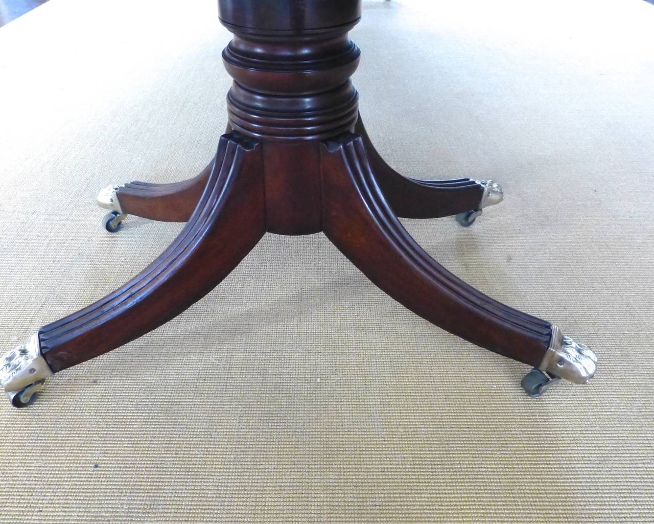 An English mahogany neoclassical two-pedestal dining table with three removable leaves extending to 13 ft. There are two leaves of 25 in. each and one probably later 25 in. The table measures 79.5 inches when closed. The rails holding the leaves are