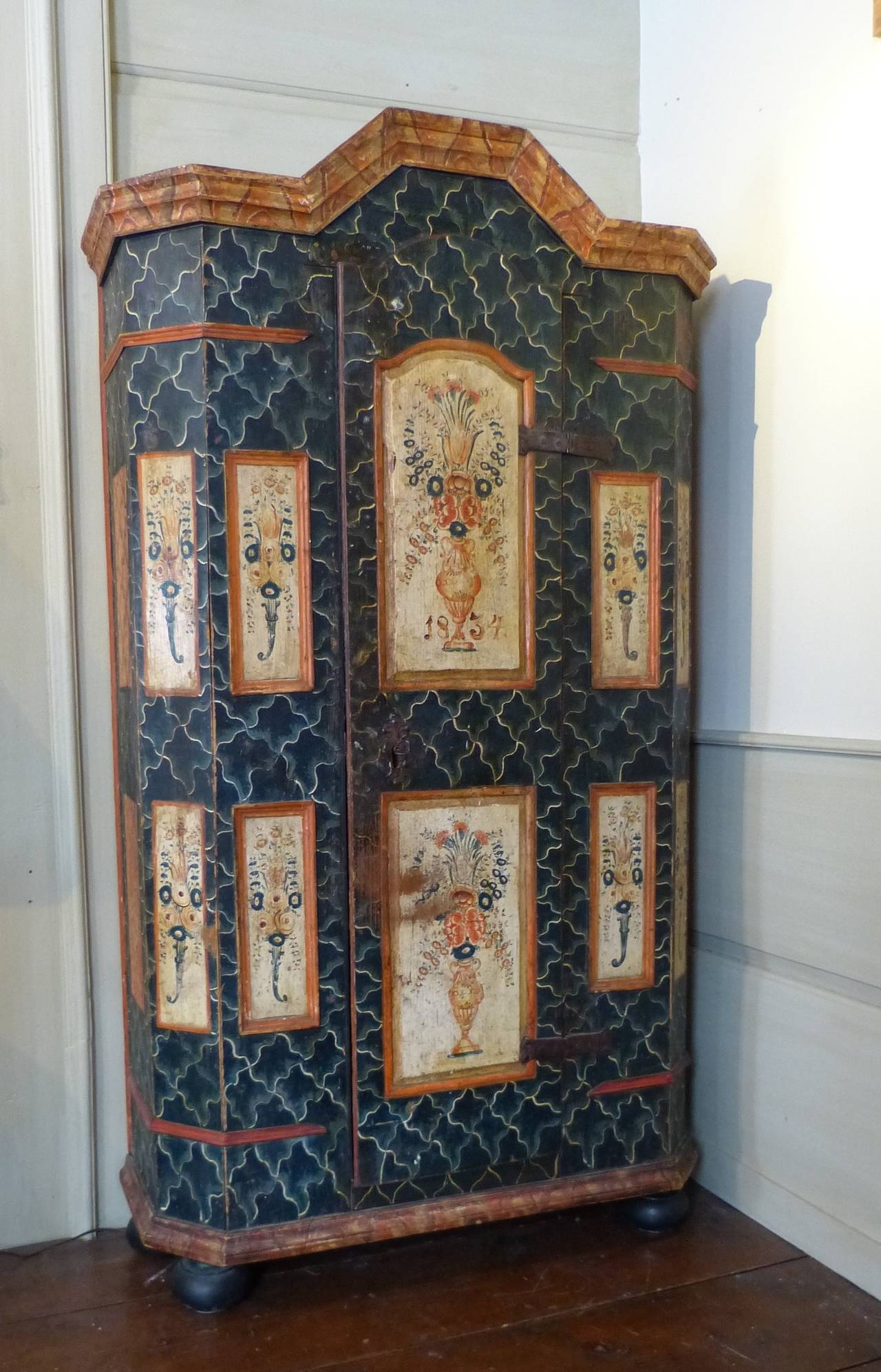 A fine Northern European painted armoire, probably Swiss. The faux marble background painted in bluish-green with ten panels on the breakfront with still life flowers in a vase. The sides with panels in brown faux marble, dated 1834.