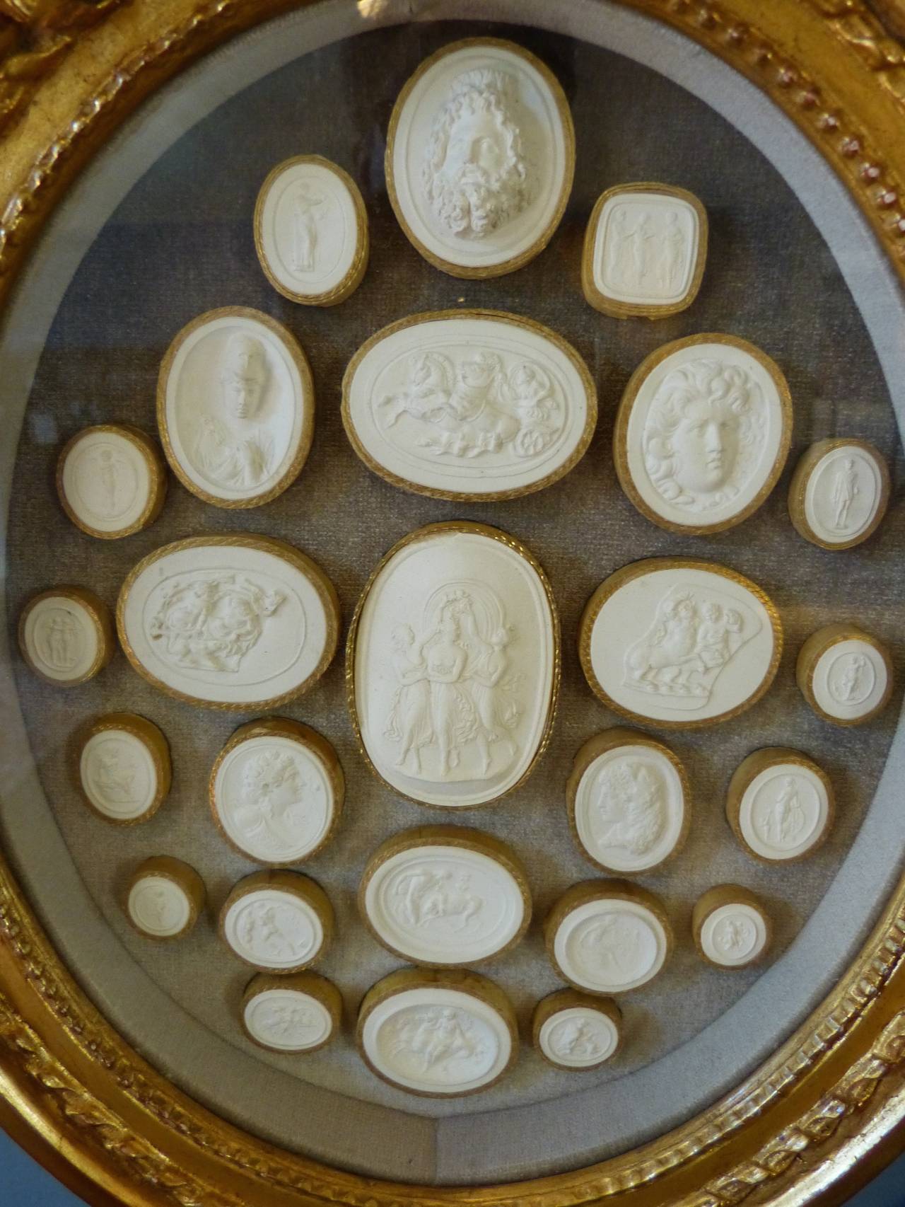 A rare set of 12 Italian 19th century oval giltwood frames with over 200 carved plaster cameos (intaglios), each surrounded by either gilt or ebonized frames. All in the subject matter in the neoclassic taste depicting Roman and Greek mythology