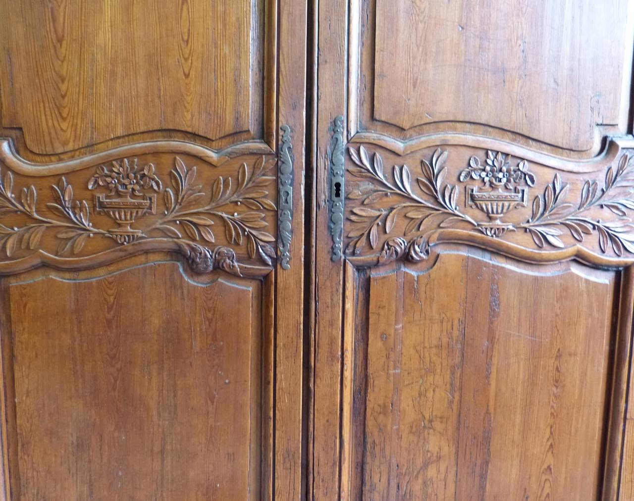 A stained pine 18th century armoire with carved decoration of vines to upper part of doors and a still life carved design to central part of the doors. The interior fitted with shelves. Depth with cornice is 56 inches, circa 1790.