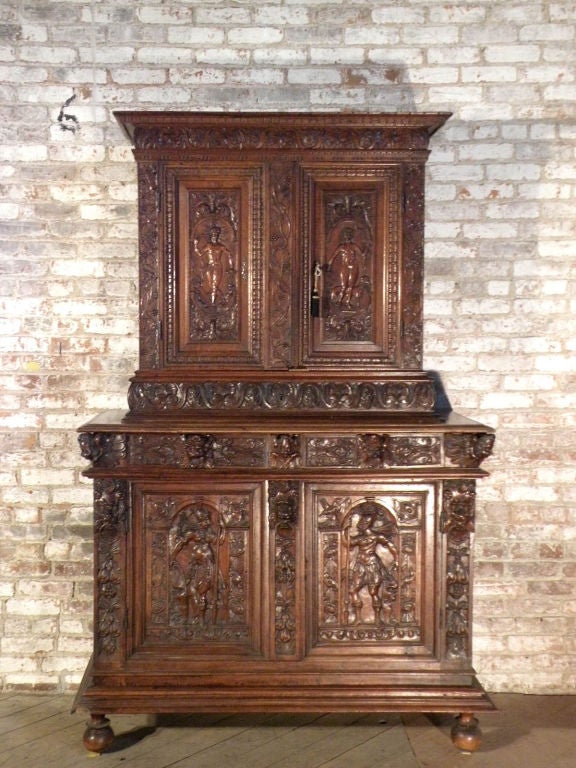 Beautiful French Renaissance cabinet in two parts. The top part with two carved doors featuring classical figures opening to an interior fitted with three small drawers at the bottom, the lower part with two similarly carved doors opening to a