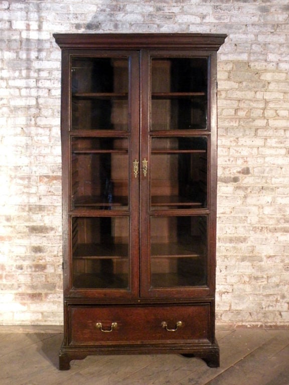 Lovely petit English bookcase with glazed doors, a deep bottom drawer and a shelved interior, on bracket feet.
Ex: S. W. Wolsey
