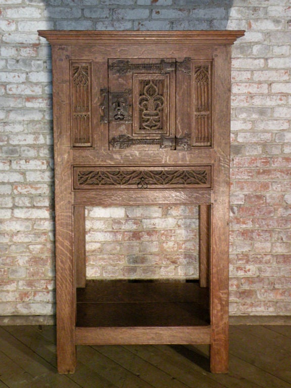 Unique and rare cabinet with an open base, finished all around, so it could be freestanding in the room, the front panels intricately carved with gothic tracery work, the side and back having simple book-fold panels. One door, adorned with elaborate