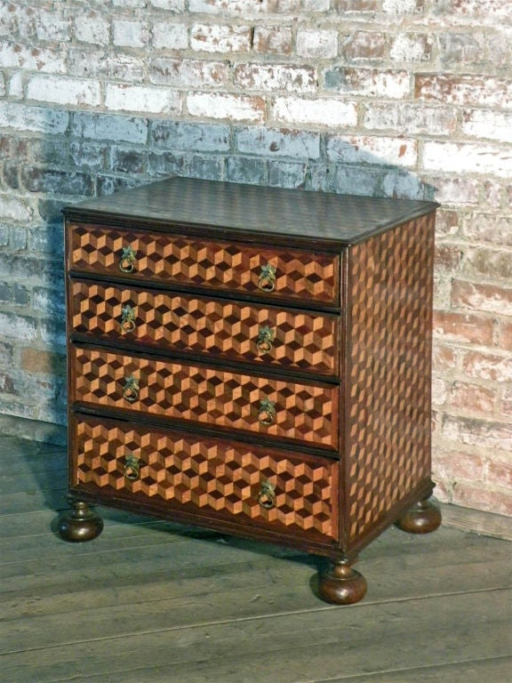 Rare, petite, decorative commode with trompe l'oeil inlay simulating cubes, featuring four drawers, on bun feet.
