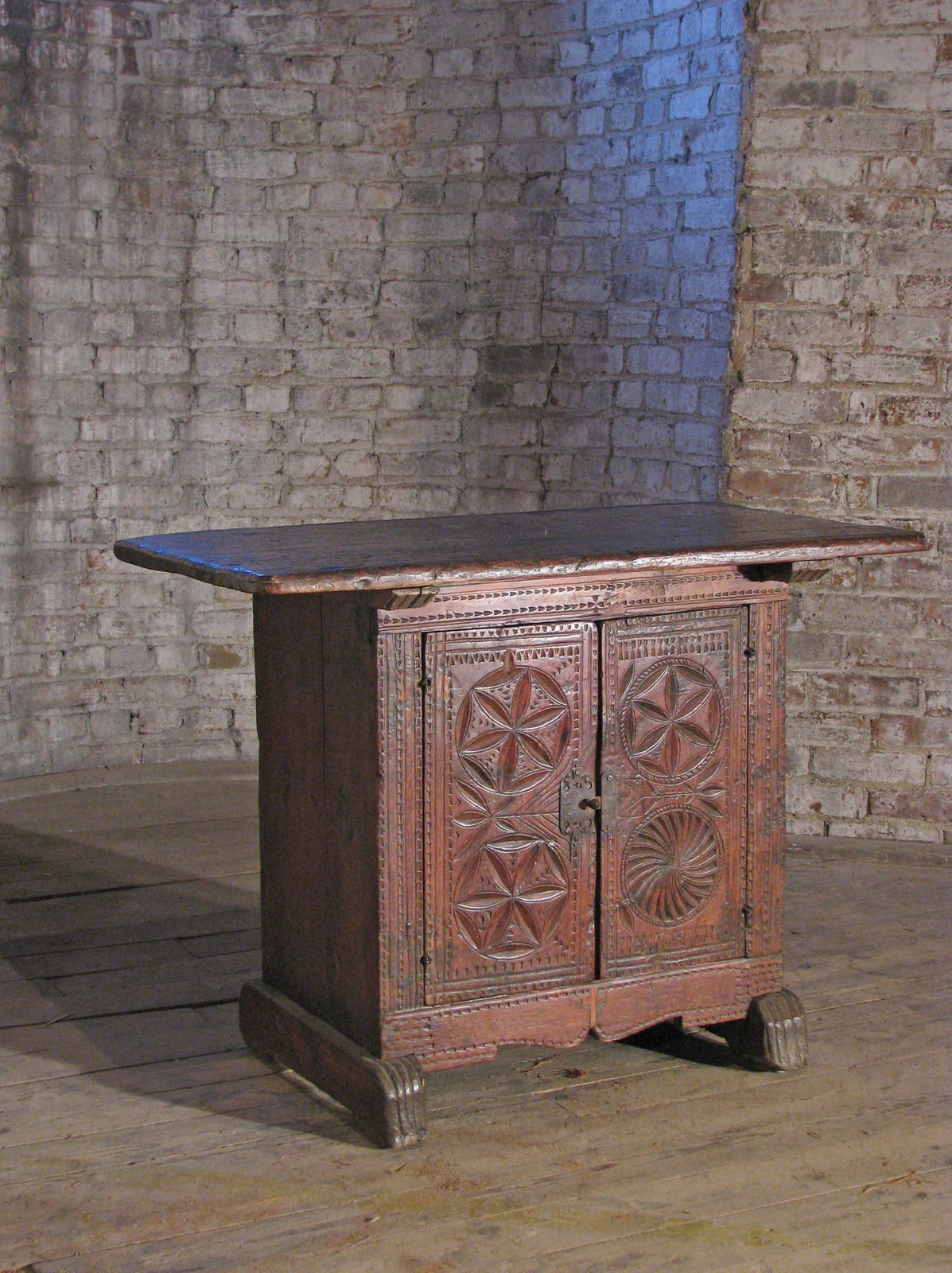 Unique and very rare piece with a rustic appearance and double function as table and / or cabinet, finished on all sides and can be freestanding. The front decorated with geometric chip-carving, sides and back with simple linear accents. Shoe-Feet