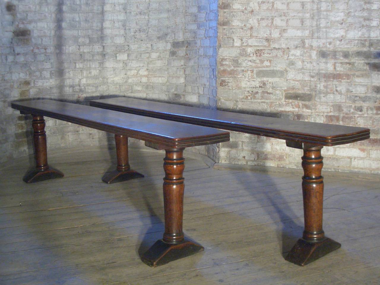 A sleek, sturdy pair of long, narrow benches, the thick, reeded top supported by turned legs on simple shoe-feet.
