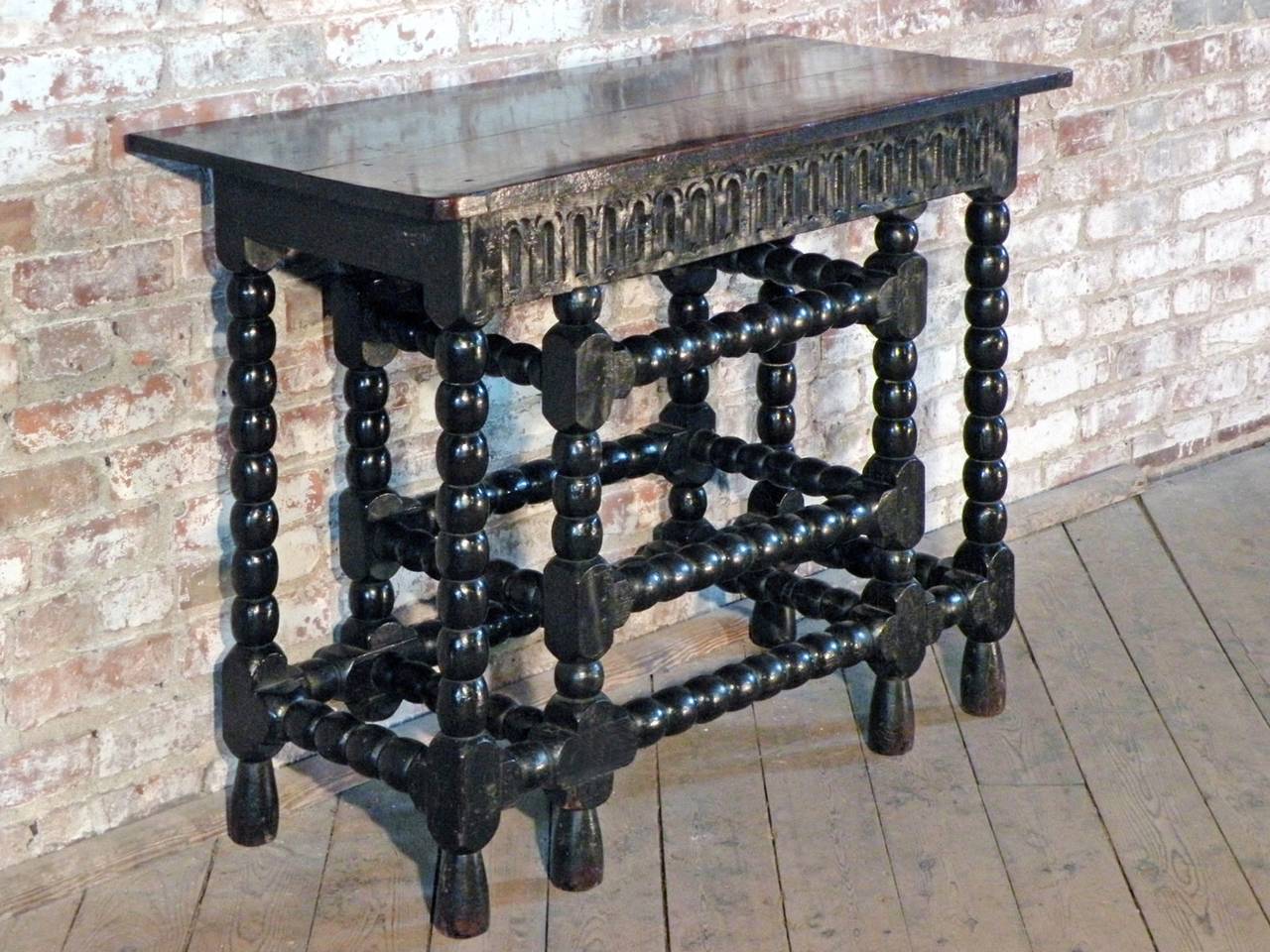 Highly unusual ebonized side / console table. A tour-de-force of bobbin-turned legs and stretchers supporting a two-board top. The black ebonizing beautifully worn off at the more exposed and touched parts. The Rhythm of interlocked vertical and