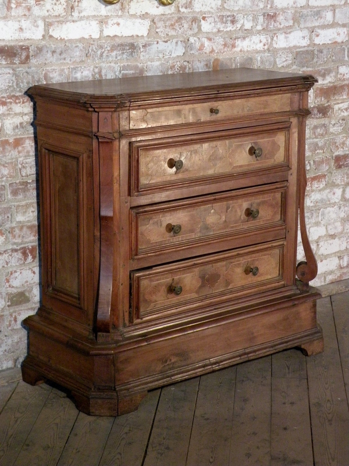Unusual Commode of Medium Size, made of Walnut and Walnut-veneer, embellished with Fruit Wood Inlay, canted corners with applied raised scroll-decoration, four drawers with molded front panels, conforming molded and inlaid side panels, raised on a
