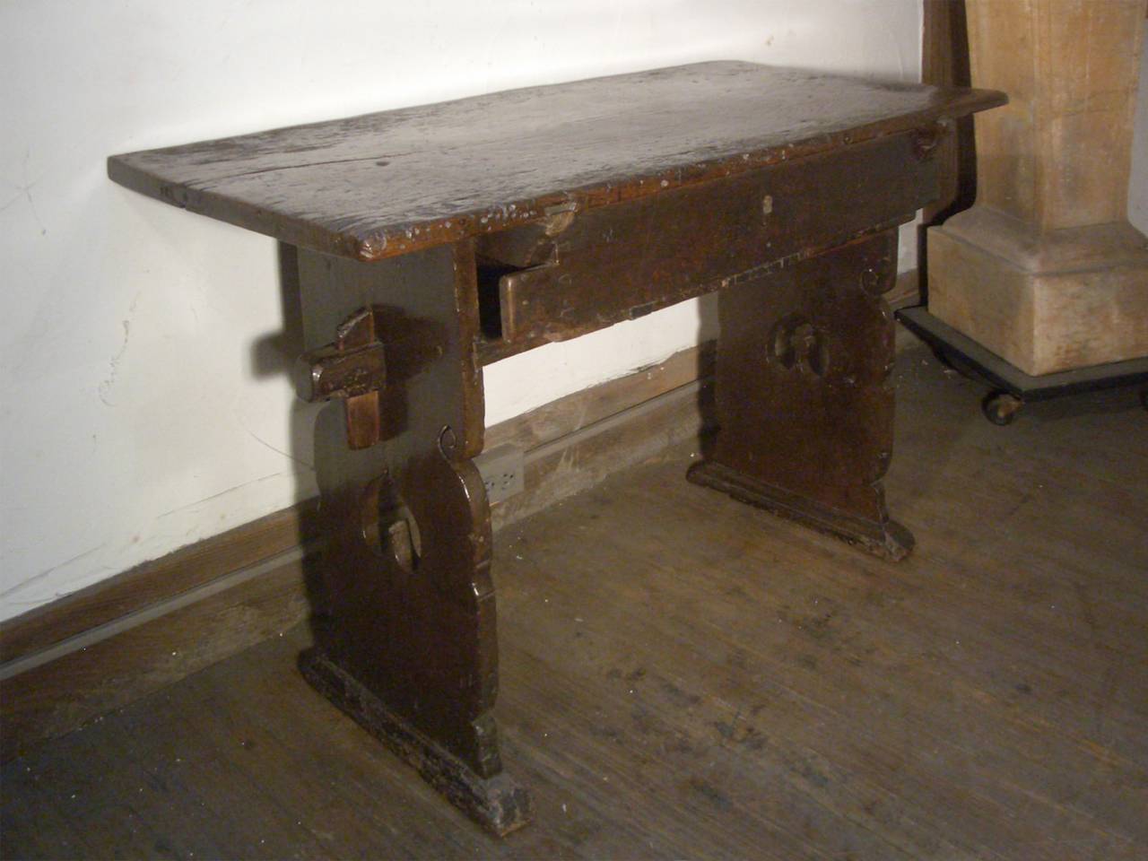 Very charming alpine table of late Gothic design, the one plank top supported by sides ending in shoe feet with simple decoration, one drawer above a connecting stretcher.
