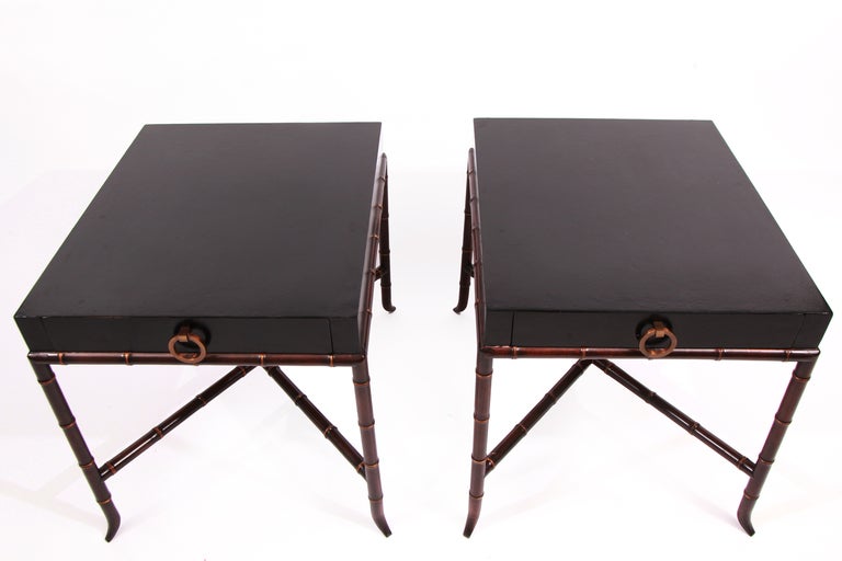 Pair of faux bamboo, parchment and bronze end or side tables circa early 1970's. These all original examples have black lacquered parchment tops, tapered faux bamboo wood legs and one drawer with bronze handles. Price is for the pair.
