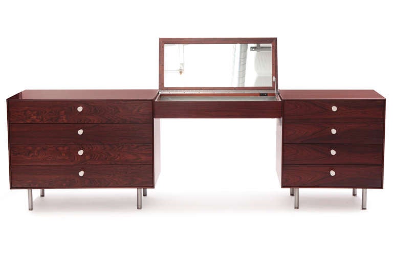 George Nelson for Herman Miller thin edge rosewood vanity, circa early 1960s. This stunning example has beautiful graining and color to the Brazilian rosewood, original white porcelain pulls and satin finished steel legs.
The center piece flips up