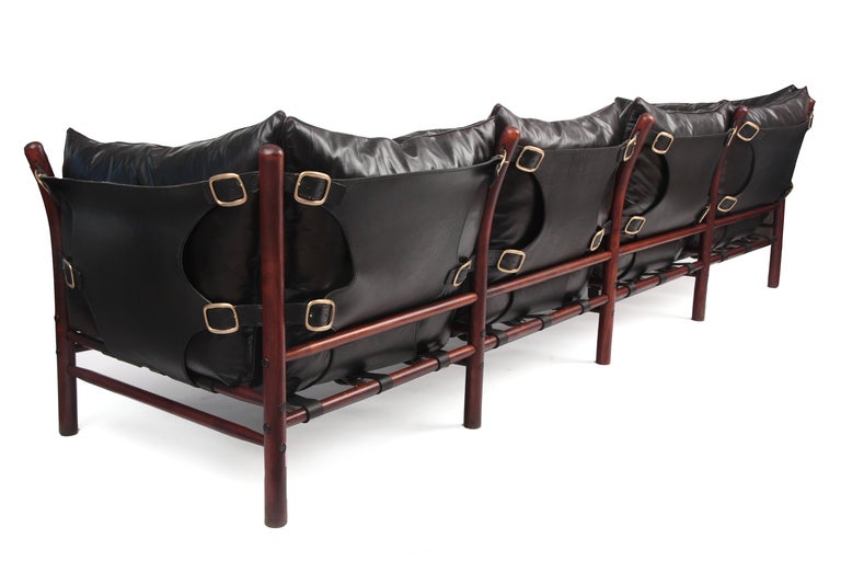Rare Arne Norell 4 seater sofa circa late 1960's. This stunning example has been newly upholstered in a supple black leather with subtle red undertones. The leather backs and sides have been newly dyed and the brass buckle detailing hand polished.