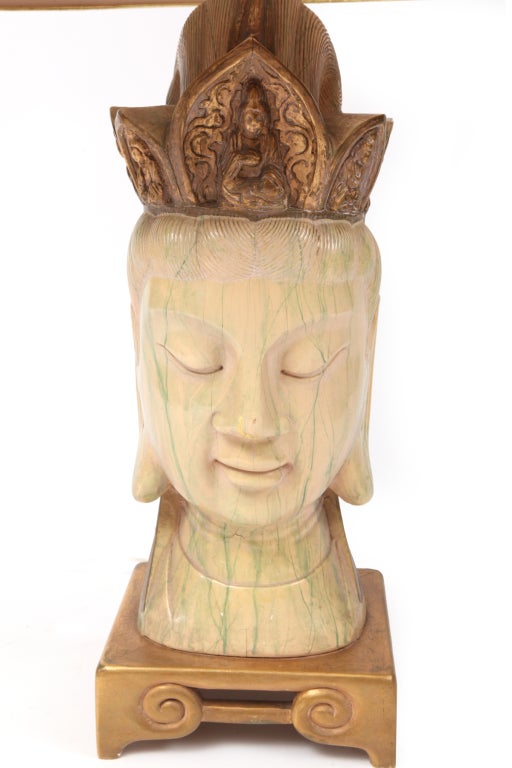 Monumental Buddha head lamp circa late 1940's. This solid hand carved example has a gold leaf base and top. The top has inset Buddha figures and the entire face is hand painted in light yellows creams and greens.