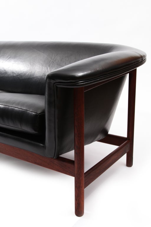 Sculptural solid teak and leather sofa from Denmark circa late 1950's. This example has a beautifully grained solid teak frame a subtly curved frame and has recently been upholstered in a supple black leather.