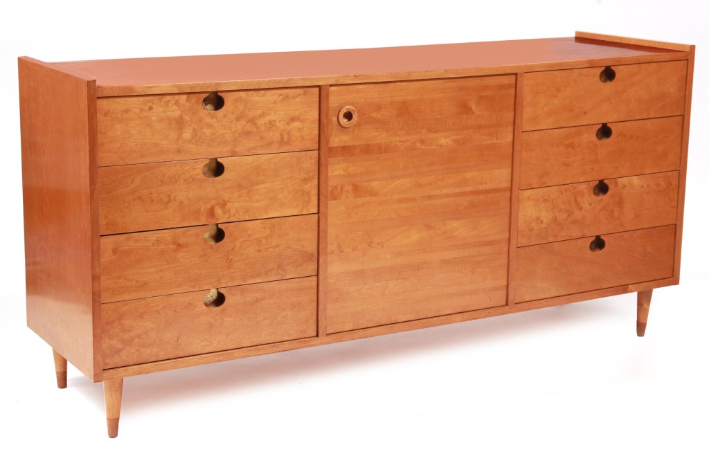 8 drawer chest of drawers by Edmond Spence circa mid 1950's. This example has beautiful flame grained maple drawer fronts, two tone maple legs and inset patinated brass pulls. The middle section has two adjustable shelves behind the maple door.