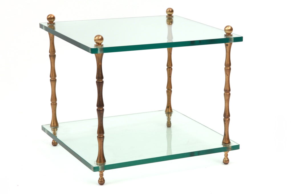 Pair of patinated brass and glass side tables, circa late 1940s. These examples have stout faux bamboo brass legs that are flanked by the original tiered glass.