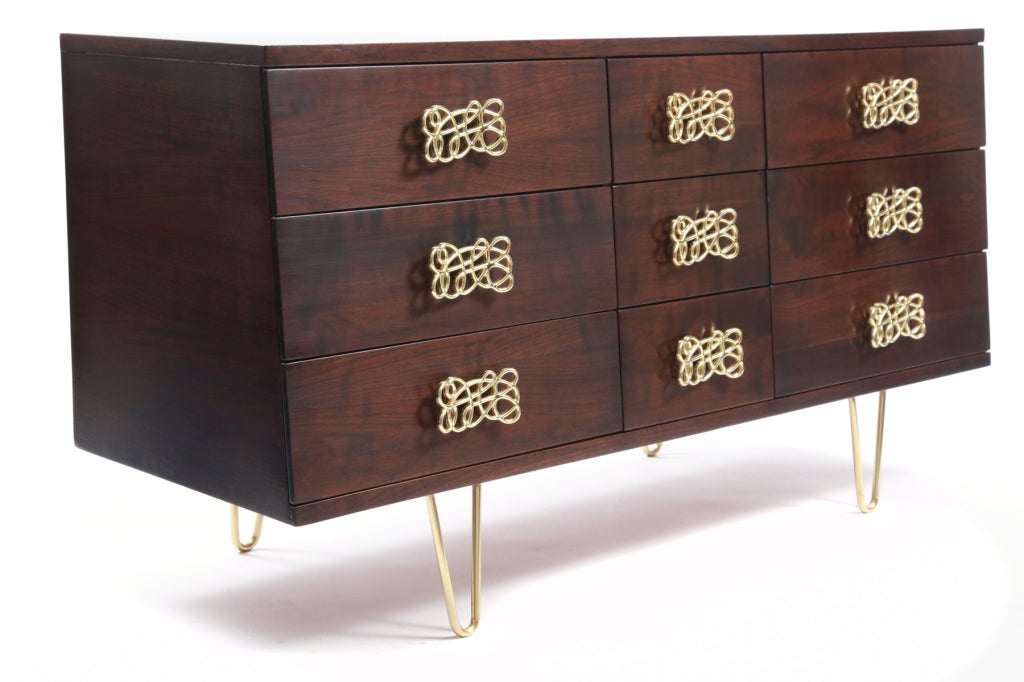 Striking walnut and polished brass chest of drawers circa late 1950's. This 9 drawer example has sculptural scraffito brass drawer pulls and hand rubbed brass hairpin legs. The walnut case has tapered sides and has been impeccably refinished. Please