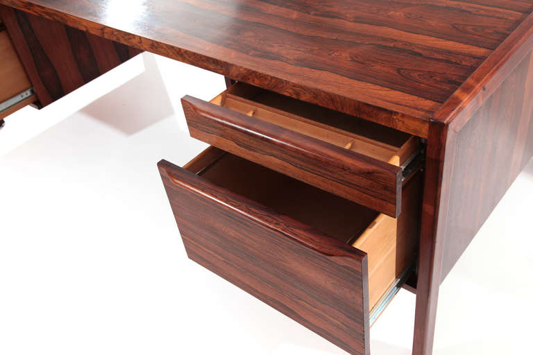 Incredibly grained rosewood executive desk from Norway circa early 1960s. This stunning all original example has four drawers with solid rosewood sculpted pulls, finished back and solid rosewood frame and legs. The top does have some slight