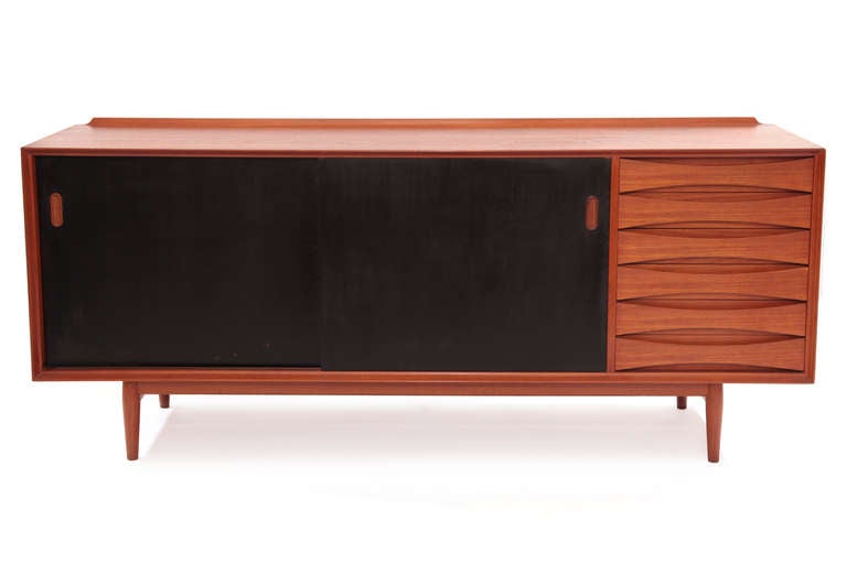Arne Vodder for Sibast teak credenza, circa late 1950s. This all original example has six drawers with iconic cut-out drawer pulls, reversible sliding doors (ebonized on one side, teak on the other), and finished back. It is in excellent original