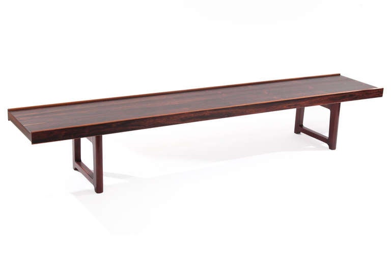 Stunning rosewood bench or cocktail table by Torbjorn Afdal for Bruksbo, circa late 1960s. This stunning example has striking graining architectural solid rosewood legs and iron stretchers. It has been impeccably restored.