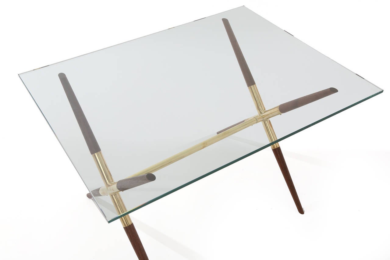 Tapered solid walnut and polished brass cocktail or occasional table from Italy, circa late 1950s. This lovely example has sculptural newly oiled walnut inserts with mirror polished brass frame. Current glass measures: 32