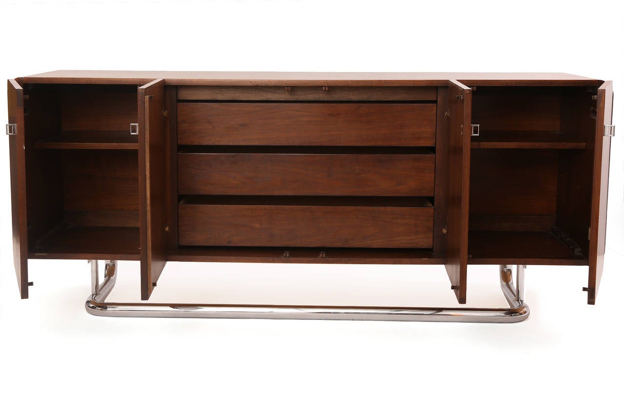 Fabulous cantilevered walnut and chrome sideboard or credenza, circa early 1970s. This all original example has beautiful graining to the walnut, four doors with square chrome pulls and ample interior storage with adjustable shelves and drawers. The