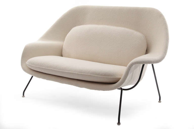 Rare and early Eero Saarinen for Knoll Womb settee circa 1950. This sculptural example has the earliest wood frame patinated black iron legs and has been newly upholstered in a Knoll's Pearl Classic Boucle.