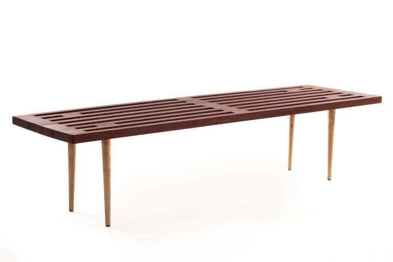 Solid walnut and patinated brass bench circa mid 1960's. this example has solid walnut slats that sit atop four conical brass legs.