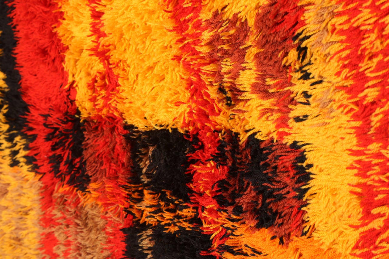 Large-scale Rya rug from Sweden, circa mid-1960s. This example seamlessly blends hues of reds oranges yellows and back in a higher pile rug.