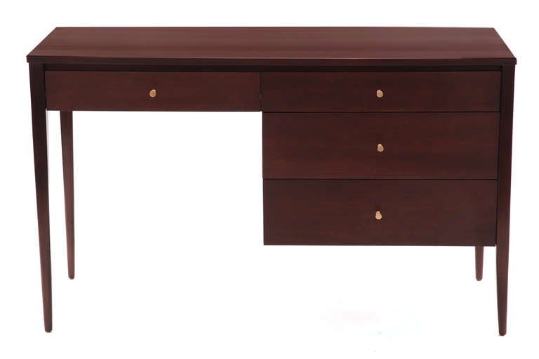 Paul McCobb for Winchendon solid maple desk, circa mid 1950s. This striking example has four drawers with hour shaped brass pulls and has been recently impeccably finished in a chocolate brown lacquer.