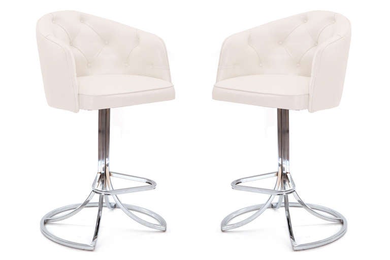 Sculptural pair of leather and chrome swivel barstools, circa early 1970s. These examples have diamond button tufted seat backs and chrome-plated steel bases with foot rests. The bases have recently been polished and the upholstery done in a supple