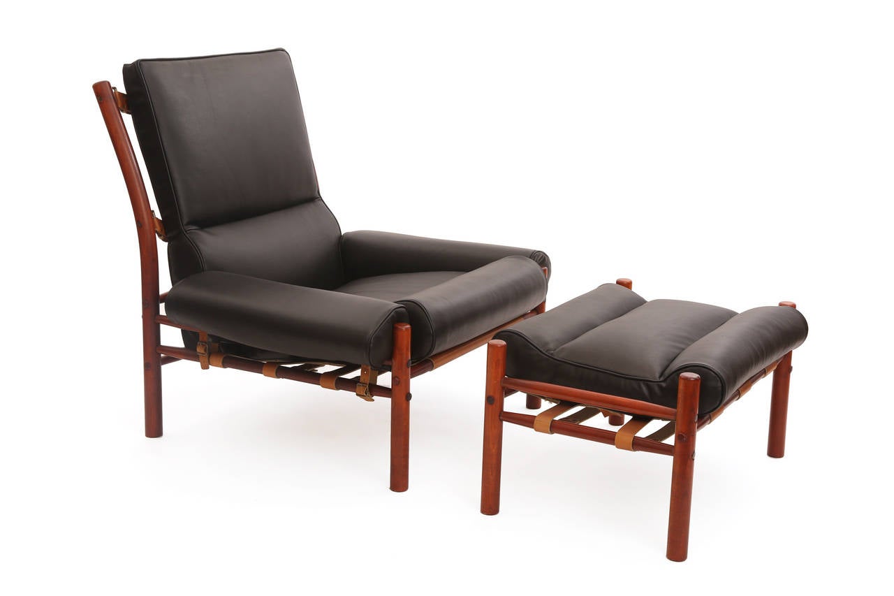 Stunning Arne Norell leather lounge chair and ottoman, circa late 1960s. This example has chocolate brown leather backs, brass buckle detailing and has been newly upholstered in black leather. Ottomans measure 16