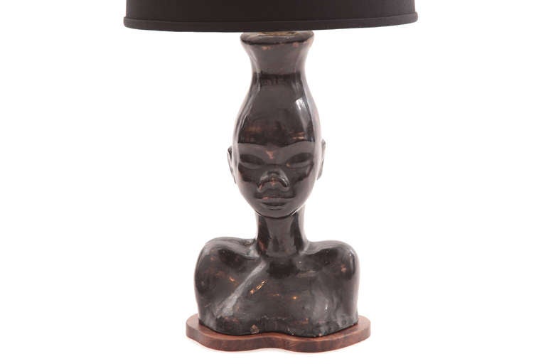 African bust lamp circa early 1950s. This example has a solid walnut base with a glazed ceramic form.