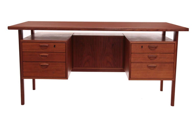 Floating teak desk by Kai Kristiansen, circa late 1950s. This example has three open shelves on the back, floating teak top and 6 drawers with inset teak handles. It has recently been sanded and oiled.